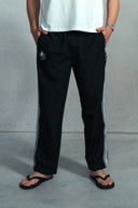 Person wearing black 'Saint Caspar' pants with white side strip on a grey background