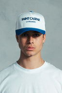 Person wearing a white and blue cap with 'SAINT CASPAR' branding against a grey background