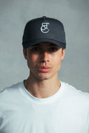 Man wearing a charcoal 'Saint Caspar' cap with a logo on a grey background